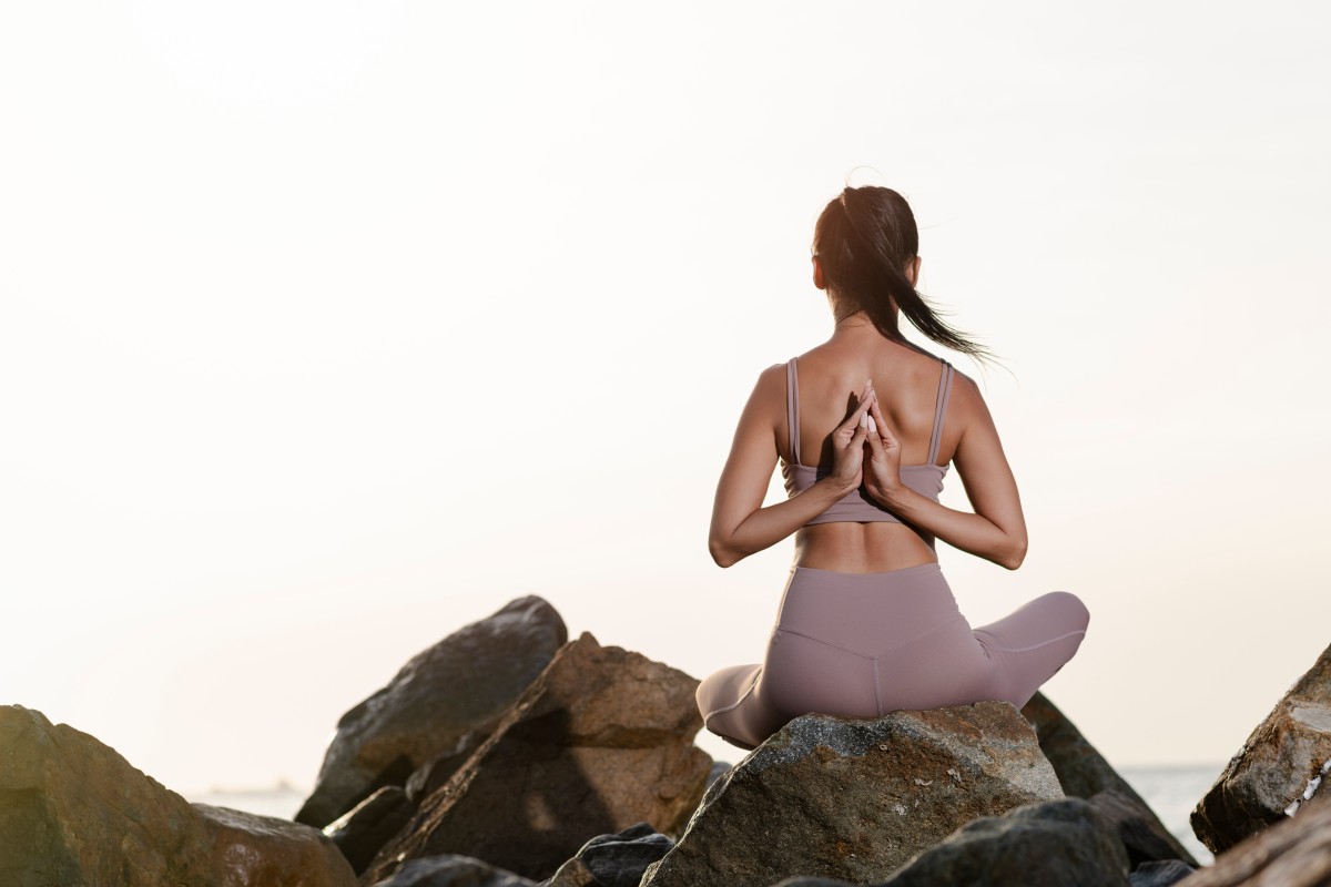 full shot woman meditating rocks 1